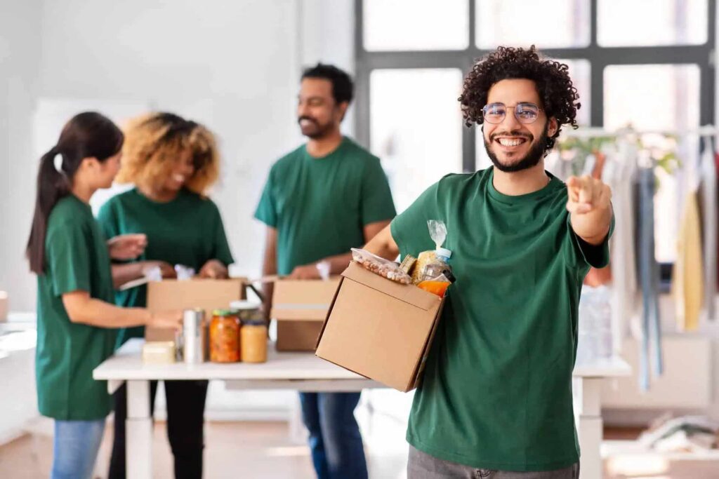 A cheerful group wearing green shirts packs food items into boxes