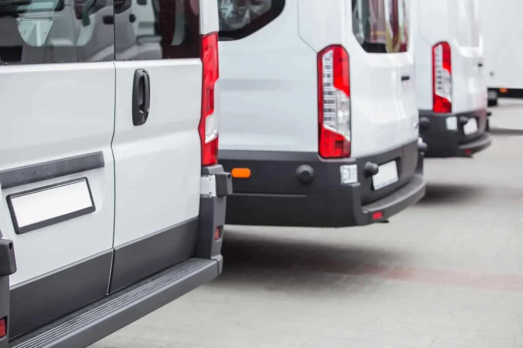 A row of white delivery vans parked closely together