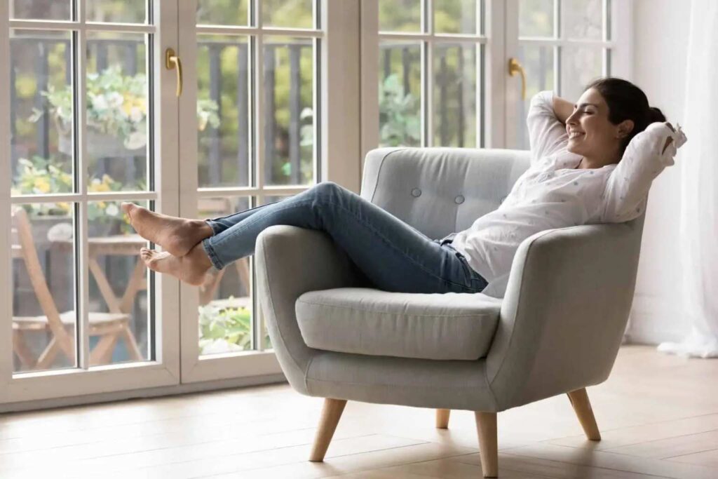 A woman in casual attire relaxes barefoot in an armchair